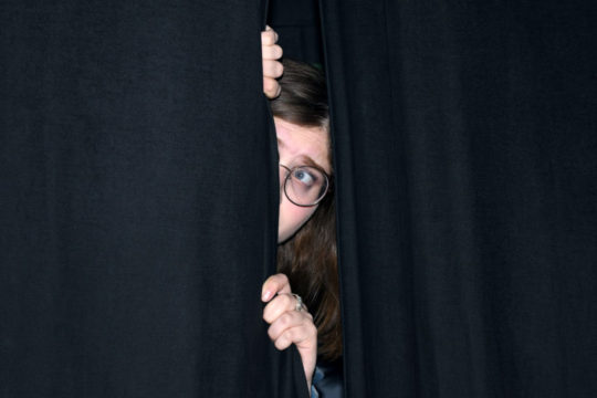 Photo of someone hiding behind show curtain